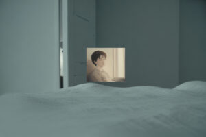 Seseorang duduk tenang memandangi jendela dengan ekspresi reflektif dan sunyi